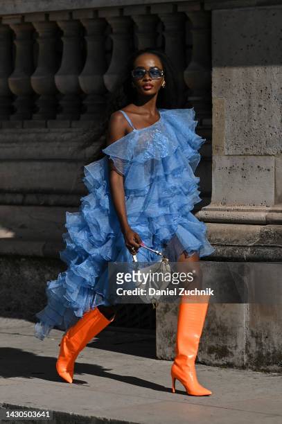 Guest is seen wearing a ruffled sheer blue dress, Dior bag and orange boots outside the Louis Vuitton show during Paris Fashion Week S/S 2023 on...