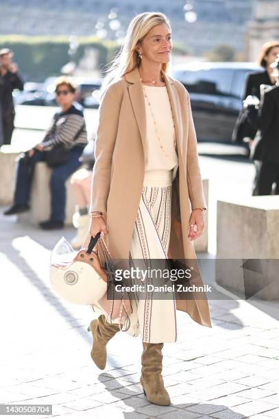 Guest is seen wearing a tan coat, cream sweater, white striped pants and white and brown helmut outside the Louis Vuitton show during Paris Fashion...