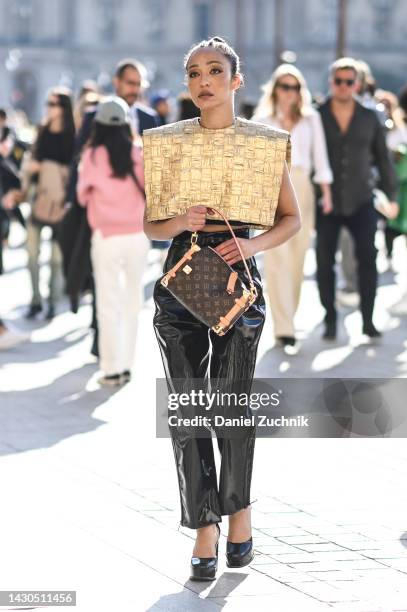 Ruth Negga is seen wearing a gold Louis Vuitton top, Louis Vuitton bag and black pants outside the Louis Vuitton show during Paris Fashion Week S/S...
