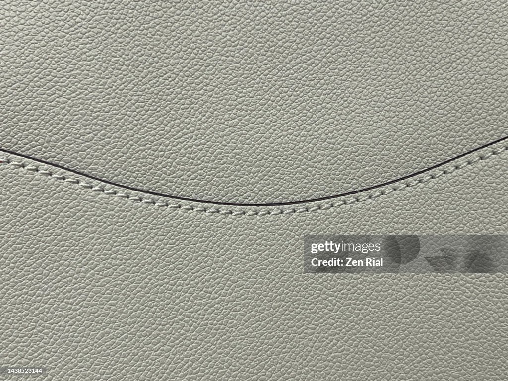 Part of a taupe-colored handbag showing texture and stitching