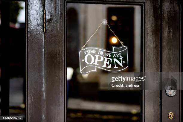 open sign hanging on the door of a restaurant - café stockfoto's en -beelden