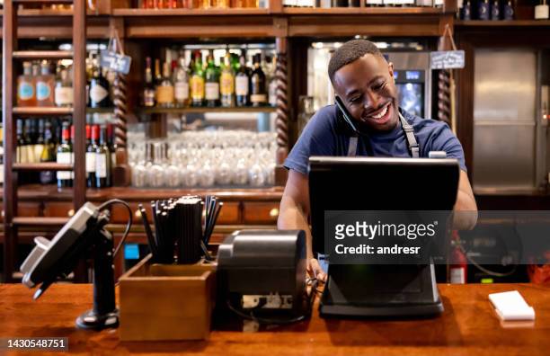cameriere felice che parla di un ordine di consegna al telefono mentre lavora in un ristorante - setting the bar foto e immagini stock