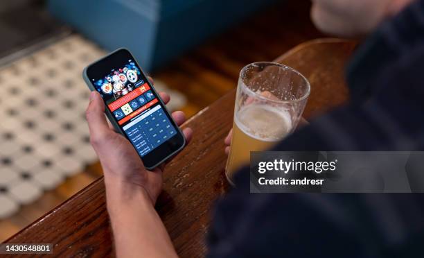 mann, der online spielt, während er bier in der kneipe trinkt - sports betting stock-fotos und bilder