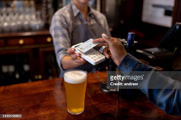 nahaufnahme eines mannes, der in der kneipe kontaktlos bezahlt - buying beer stock-fotos und bilder