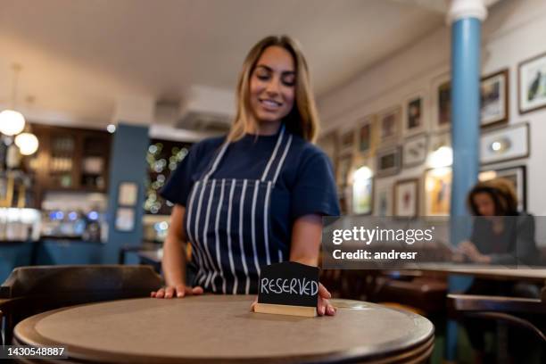 waitress placing a reserved sign on a table at a restaurant - reserved sign stock pictures, royalty-free photos & images