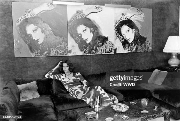 Model wears a Diane von Furstenberg seagull-printed wrap dress and poses in the designer's apartment. An Andy Warhol portrait of Diane von...