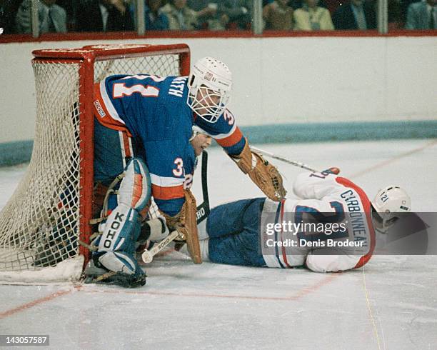 Billy Smith of the New York Islanders knocks down Guy Carbonneau of the Montreal Canadiens as he skates through the crease Circa 1980 at the Montreal...