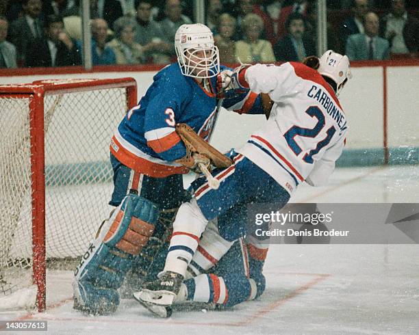 Billy Smith of the New York Islanders knocks down Guy Carbonneau of the Montreal Canadiens as he skates through the crease Circa 1980 at the Montreal...