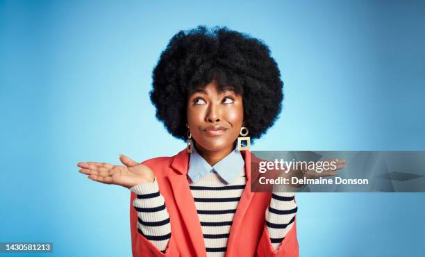 thinking, confused and shrugging woman doubt, puzzled and unsure about choice, decision and idea in mind against blue background. thoughtful african afro female with faq, question and open hands - verwarring stockfoto's en -beelden