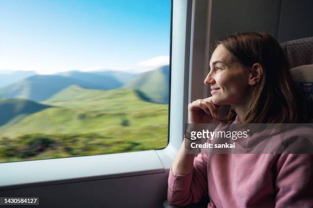 pretty woman travelling on the train. woman looking through the window on beautiful landscape - train window stock pictures, royalty-free photos & images