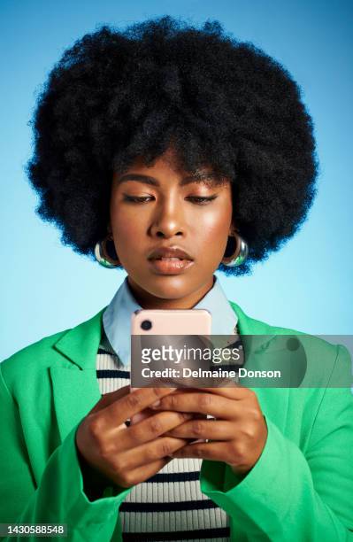 black woman with phone reading social media, news or post online and text message to contact against blue mock up studio background. afro model on the internet with a mobile smartphone app with 5g - media buying stock pictures, royalty-free photos & images