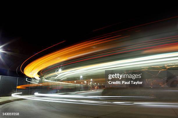 lights streaking in arc at night - strassen nacht stadt stock-fotos und bilder