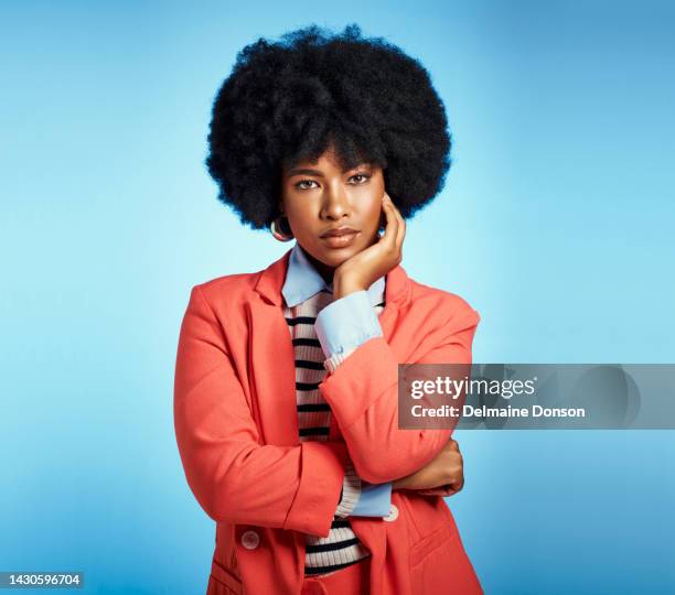 stylish, fashion and serious black woman with an afro and beautiful face while standing against a blue studio background. portrait of an african female feeling confident in a smart casual suit - dark skin tone stock pictures, royalty-free photos & images