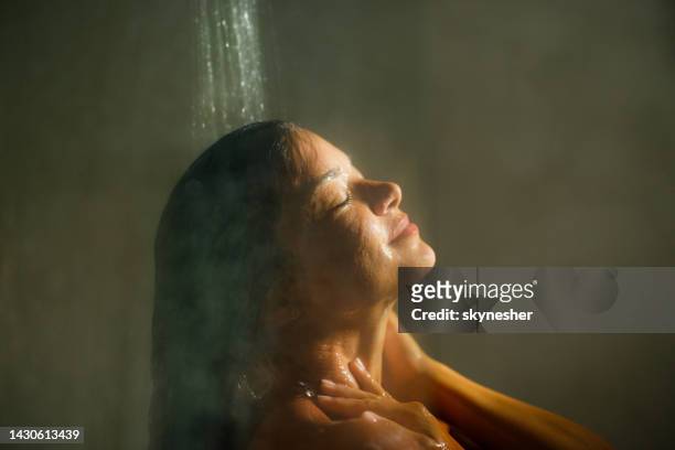 woman enjoying while washing hair with her eyes closed. - haar wassen stockfoto's en -beelden