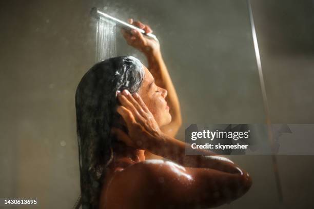 mujer disfrutando mientras se lava el cabello con los ojos cerrados. - lavarse el cabello fotografías e imágenes de stock