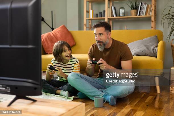 boy and his dad gaming and having fun at home - boy at television stock pictures, royalty-free photos & images
