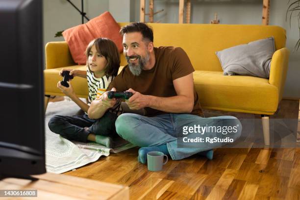 boy and his dad playing video games on a weekend evening - foster parent stock pictures, royalty-free photos & images