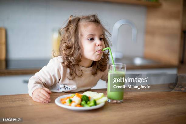 süßes babymädchen, das grünen smoothie trinkt und gemüse isst - fresh baby spinach stock-fotos und bilder