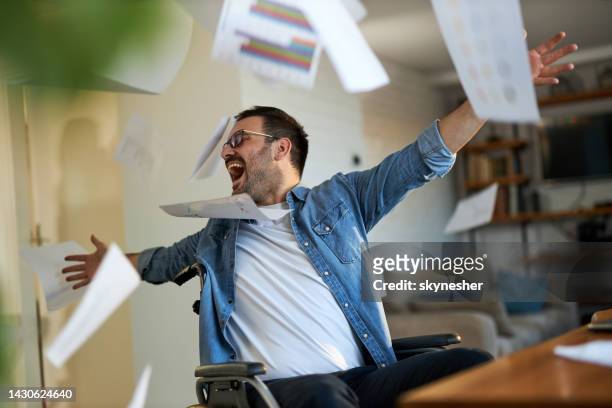 carefree disabled businessman throwing paperwork at home office. - flip over stockfoto's en -beelden