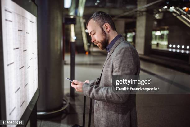 checking the train on the time table - travel insurance stock pictures, royalty-free photos & images