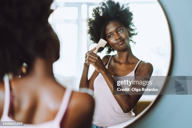 fight with wavy hair, afro hairstyle problem. tired woman combing wavy fluffy black hair in front of the mirror - black hair texture stock pictures, royalty-free photos & images