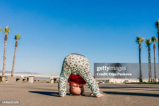 toddler baby stands upside down  at square with palm trees. - 1歳以上2歳未満 ストックフォトと画像