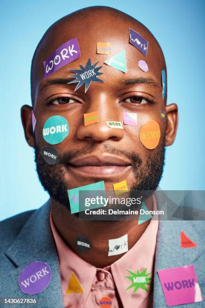 tired, overworked and portrait of a businessman with stickers on his body and face standing in studio. closeup of burnout professional black guy with work sticky notes on his head by blue background. - man blue background stockfoto's en -beelden