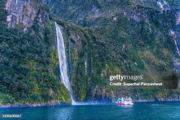 tour boat at great waterfall in milford sound, milford sound national park, new zealand - milford sound stock pictures, royalty-free photos & images