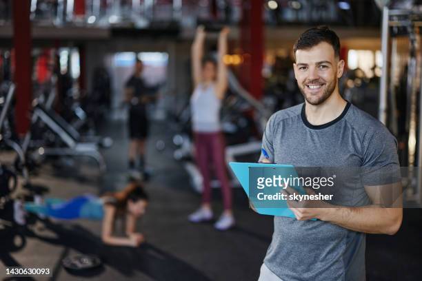 happy male coach writing plans in a health club. - personal trainer stock pictures, royalty-free photos & images
