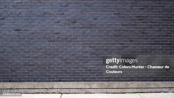 empty and weathered dark gray brick wall and cement sidewalk in montreal, qc, canada - brick wall stockfoto's en -beelden