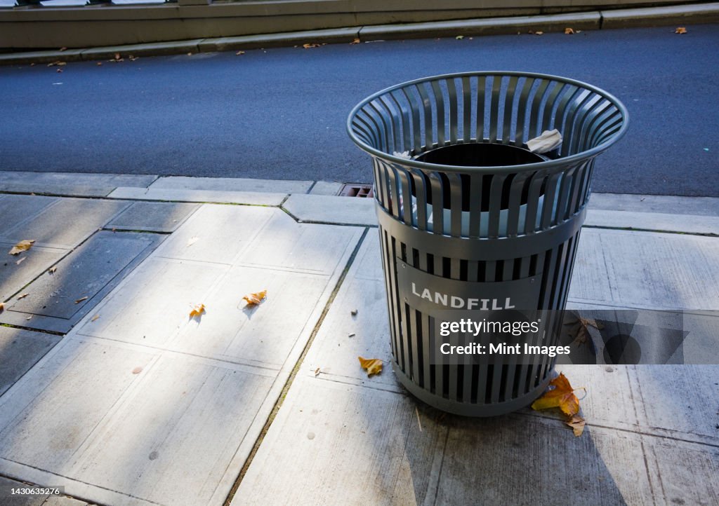 A garbage can on the sidewalk in the city