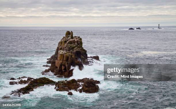 land's end, rock islets offshore, the penwith peninsula, view to a lighthouse and out to sea - penwith peninsula stock pictures, royalty-free photos & images