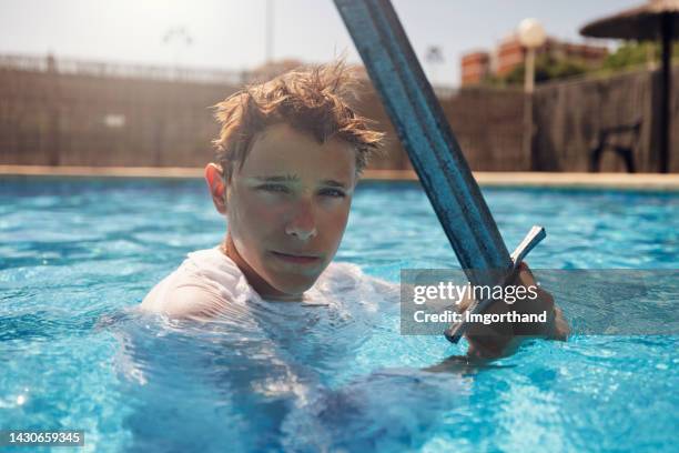 teenage boy practicing sword fighting in the pool - weird hobbies stock pictures, royalty-free photos & images