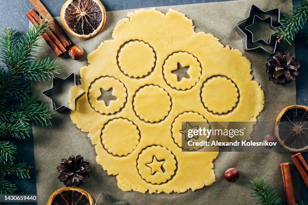 process making traditional christmas cookies. raw dough and cutters for the holiday cookies on table. - pastry cutter fotografías e imágenes de stock