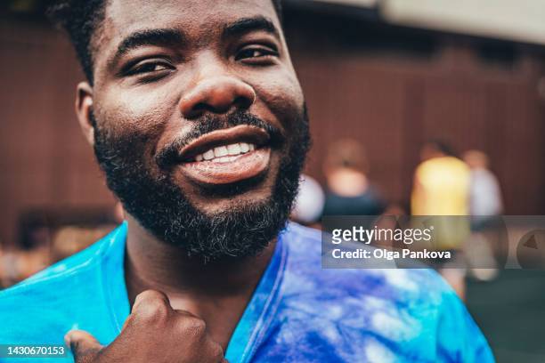 smiling black young man wearing  blue tie-dye t-shirt - social movement - fotografias e filmes do acervo