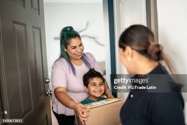 mother and son receiving package at home entrance - receiving package stock pictures, royalty-free photos & images