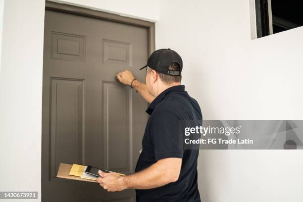 mid adult man delivering package at shipment address - knocking stockfoto's en -beelden