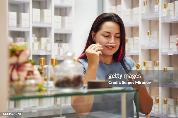 young woman choosing perfume in boutique store - choosing perfume stock pictures, royalty-free photos & images