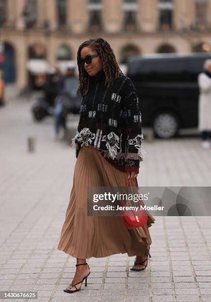 Guest is seen wearing black sunglasses, black/white wool knit fringed sweater, brown plated long skirt, red leather Ralph Lauren bag, black heels,...