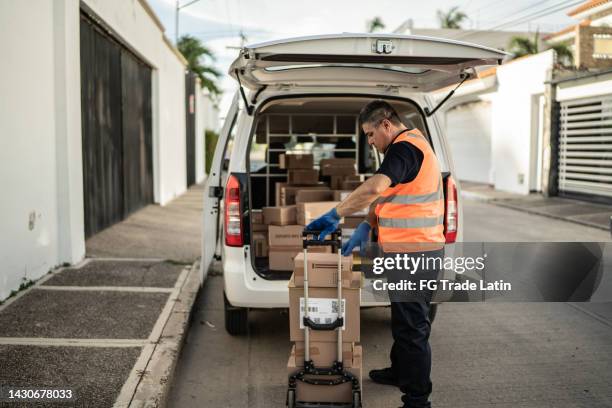 postal worker organizing van truck with cardboard boxes - tradesman van stock pictures, royalty-free photos & images