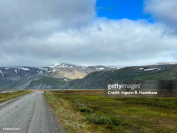dirtroad in dramatic landscape between sea and mountains. nature reserve. overcast weather with a glimpse of sun on the mountains. summer day but still some snow left from last winter. - finnmark county stock pictures, royalty-free photos & images