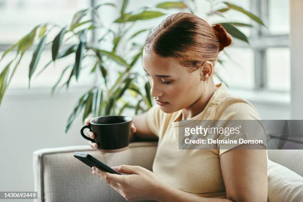 sad woman, phone and coffee of a person from atlanta with technology on a living room lounge sofa. social media, mobile and web scroll of a young female  with depression on a home couch at a house - female worried mobile imagens e fotografias de stock