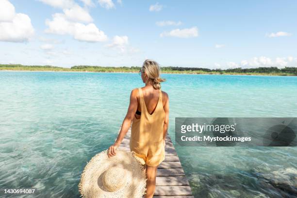 young woman walks on pier above blue lagoon - gulf of mexico oil rig stockfoto's en -beelden