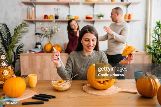 junge mutter schnitzt kürbisse für halloween - jack o lantern stock-fotos und bilder