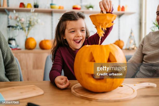 little girl carving out a pumpkin for halloween - skära mat bildbanksfoton och bilder
