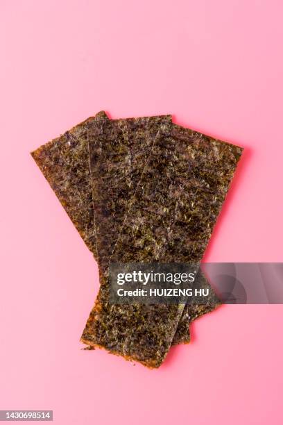 dry roasted seaweed on pink background - meeresalge stock-fotos und bilder