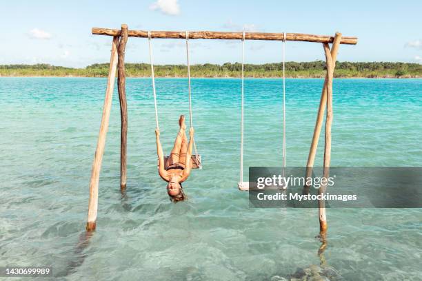 rear view of young woman swinging above blue lagoon in mexico - yucatánhalvön bildbanksfoton och bilder