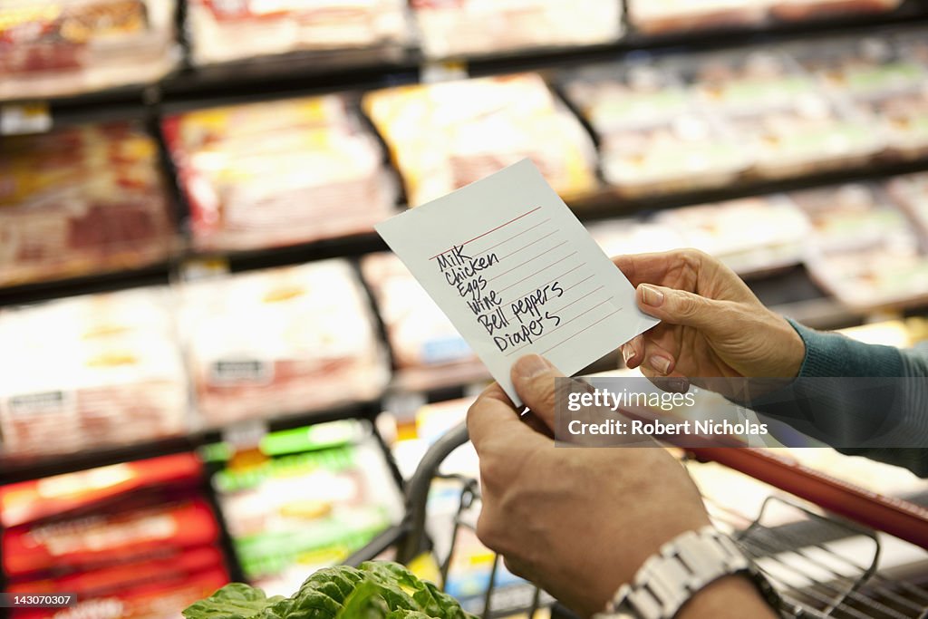 Older woman reading grocery list in supermarket