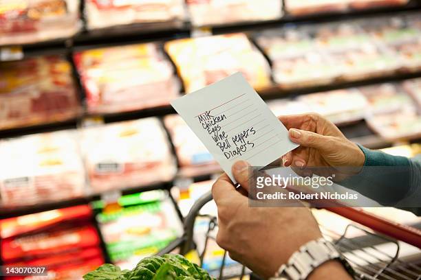older woman reading grocery list in supermarket - boodschappenlijst stockfoto's en -beelden