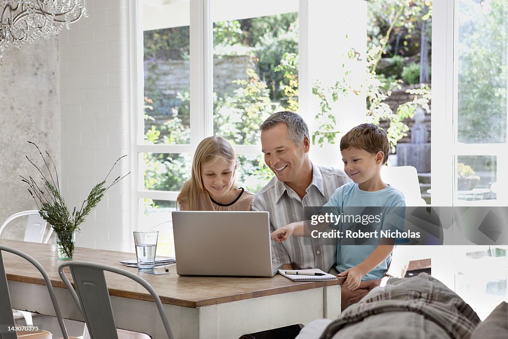 Family using laptop together at dining room table